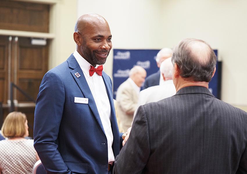 Man in bowtie and suit listening to someone talk.