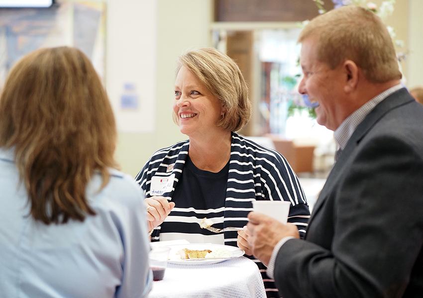 Three people talking around table.