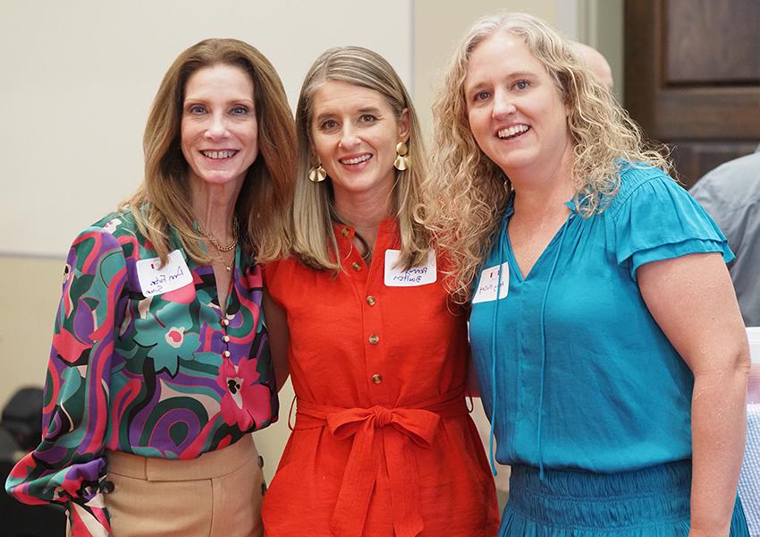 Three female alumni smiling at camera.