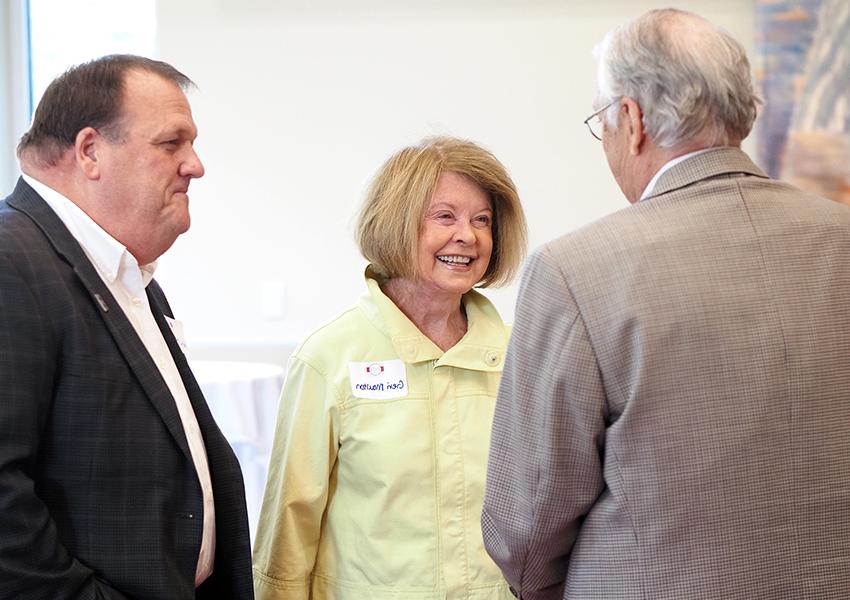 Geri Moulton smiling with two alumni.