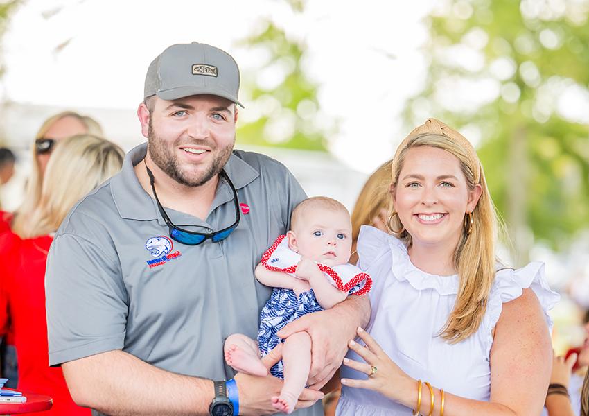 Two alumni and a child smiling.