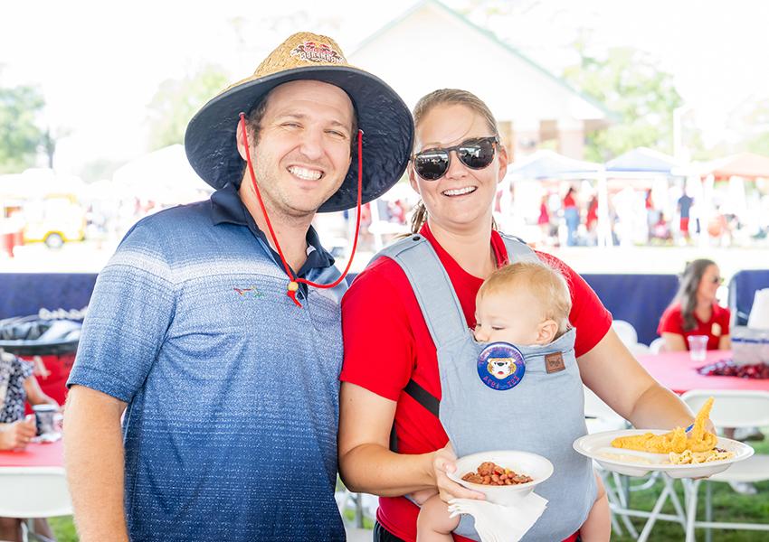 Two alumni and a child smiling.