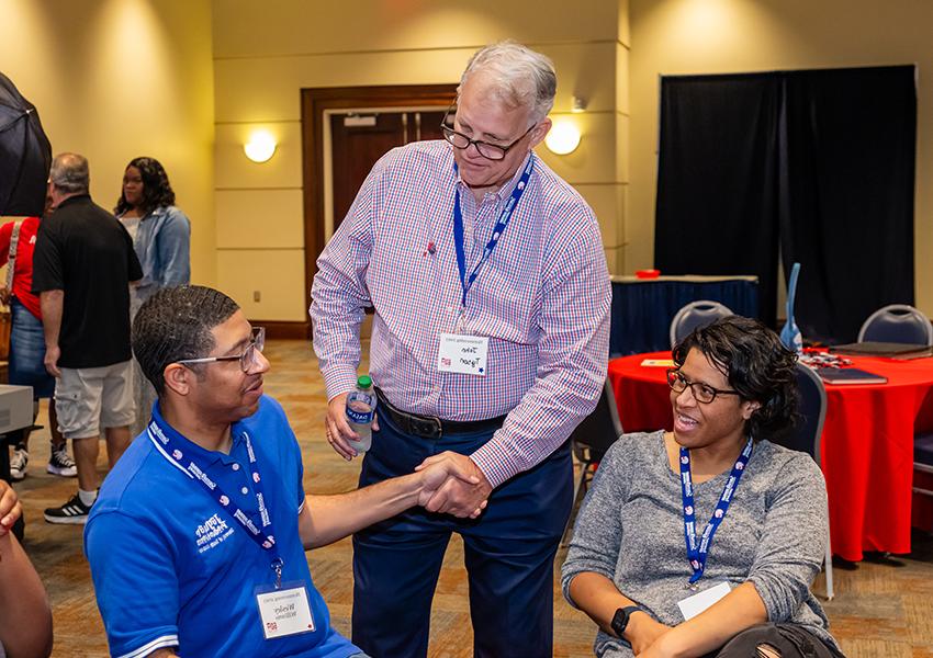 Three alumni greeting each other.