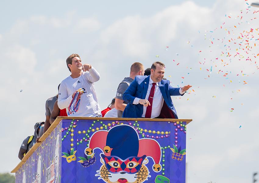 A group of alumni on a float in a parade.