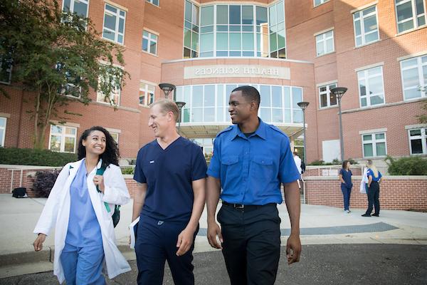 Three allied health stdent walking out of building.