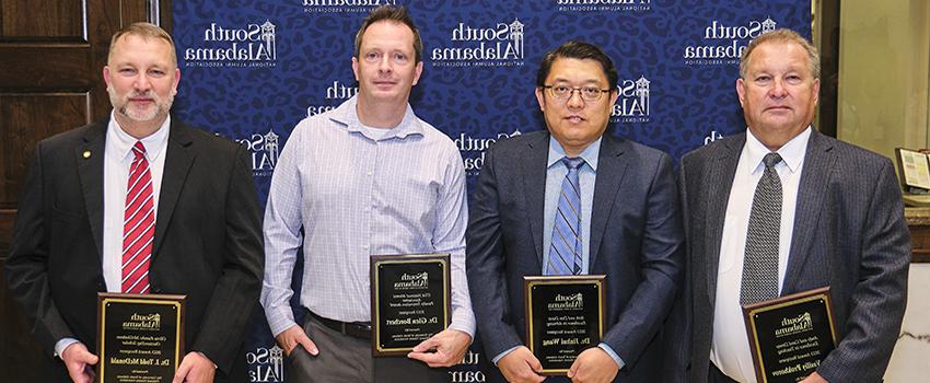 Alumni Award Winners holding their plaques.